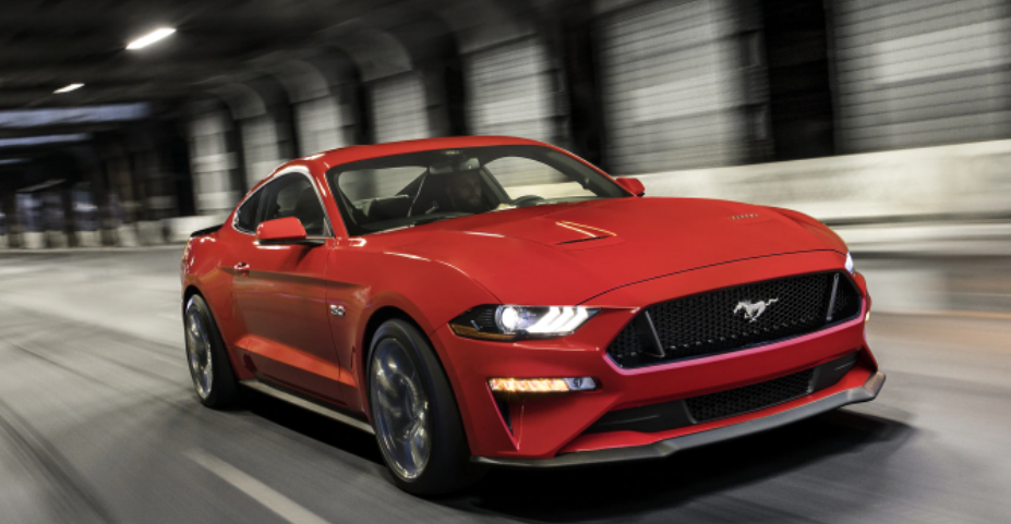 red-ford-mustang-driving-down-city-road