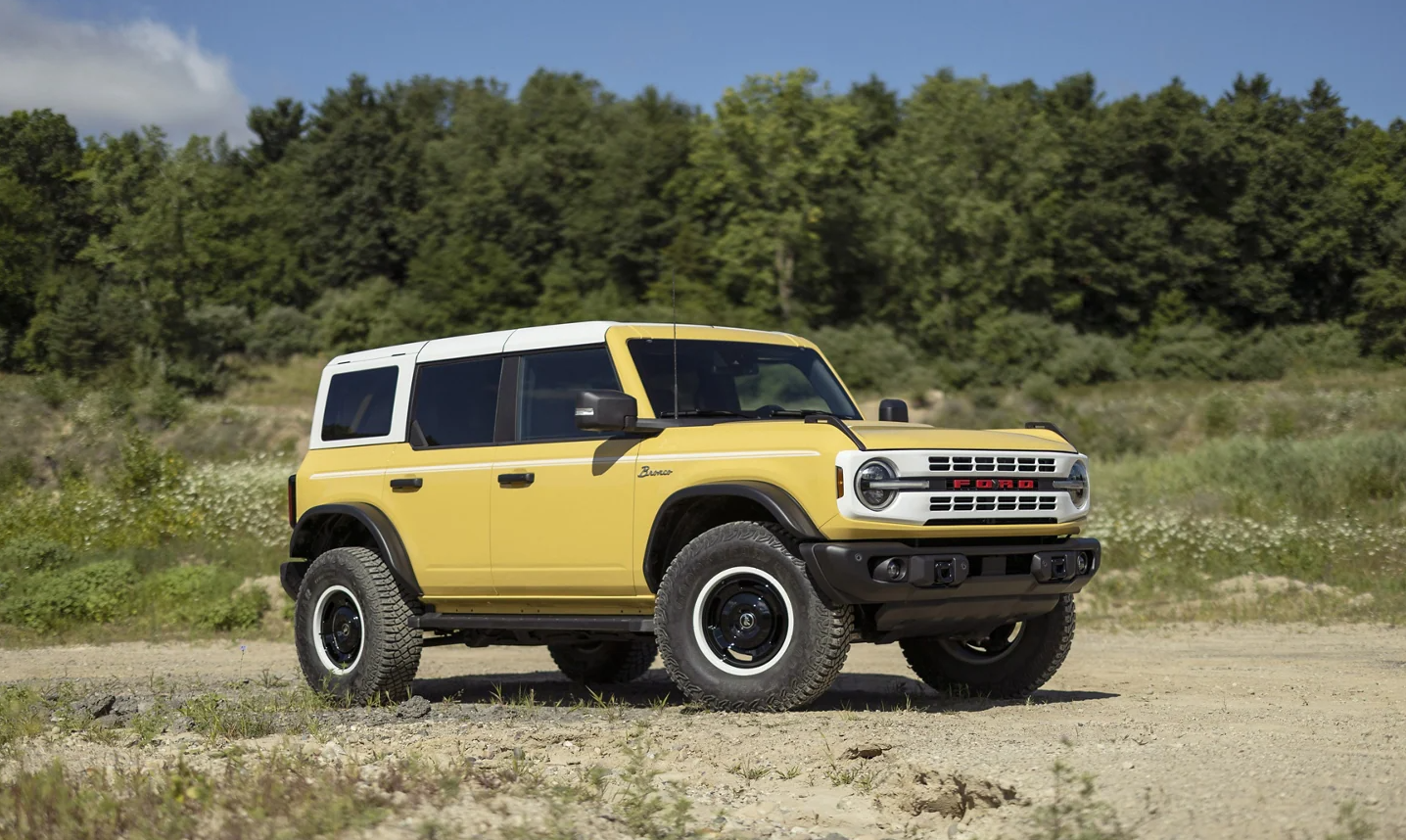 A yellow 2023 Ford Bronco with a white roof parked at a campsite.