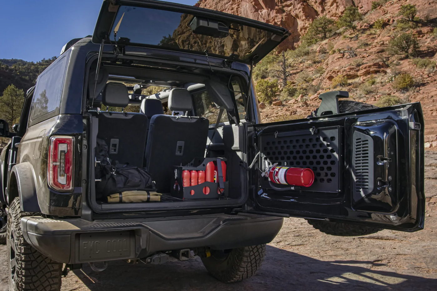 A view of the rear of a 2023 Ford Bronco with the back door swung open and showing the cargo hold full of gear.