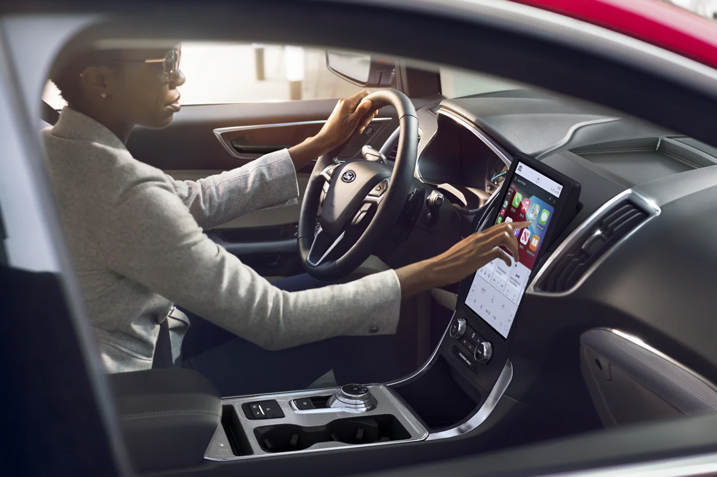 A woman sits in the driver's seat and uses the infotainment system and controls on the dash of the 2023 Ford Edge