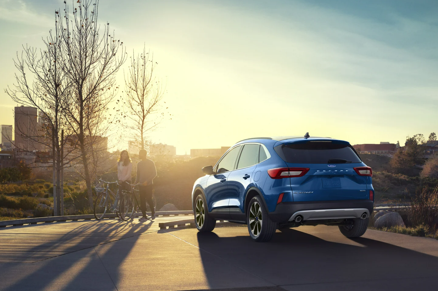 A view of the back of a blue 2023 Ford Escape parked facing a sunset.