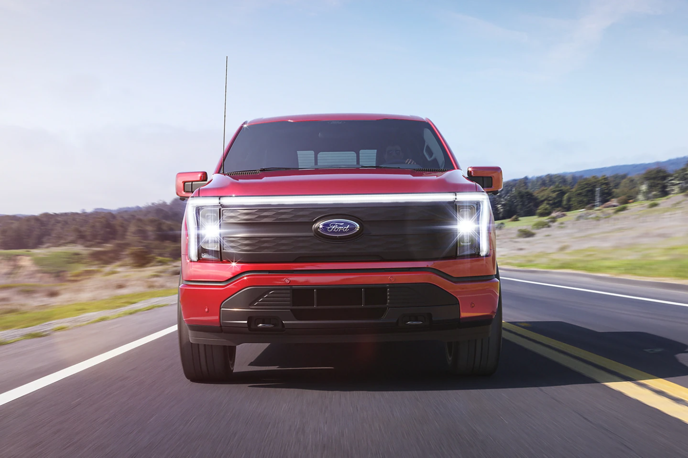 A head-on view of a red 2023 Ford F-150 Lightning as it drives toward the viewer