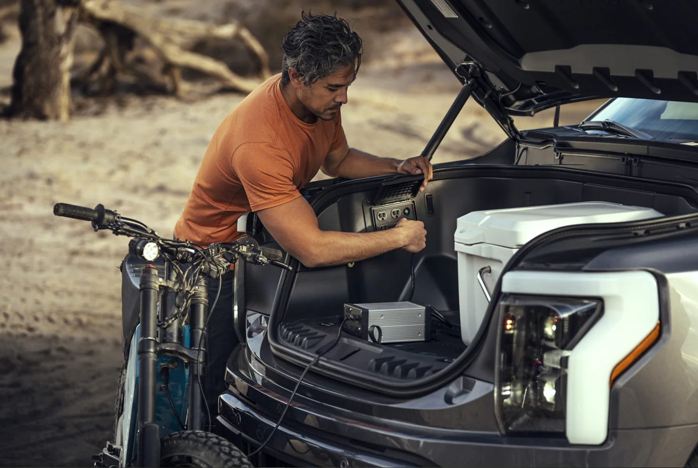 A man uses the outlet in the frunk of a 2023 Ford F-150 Lightning