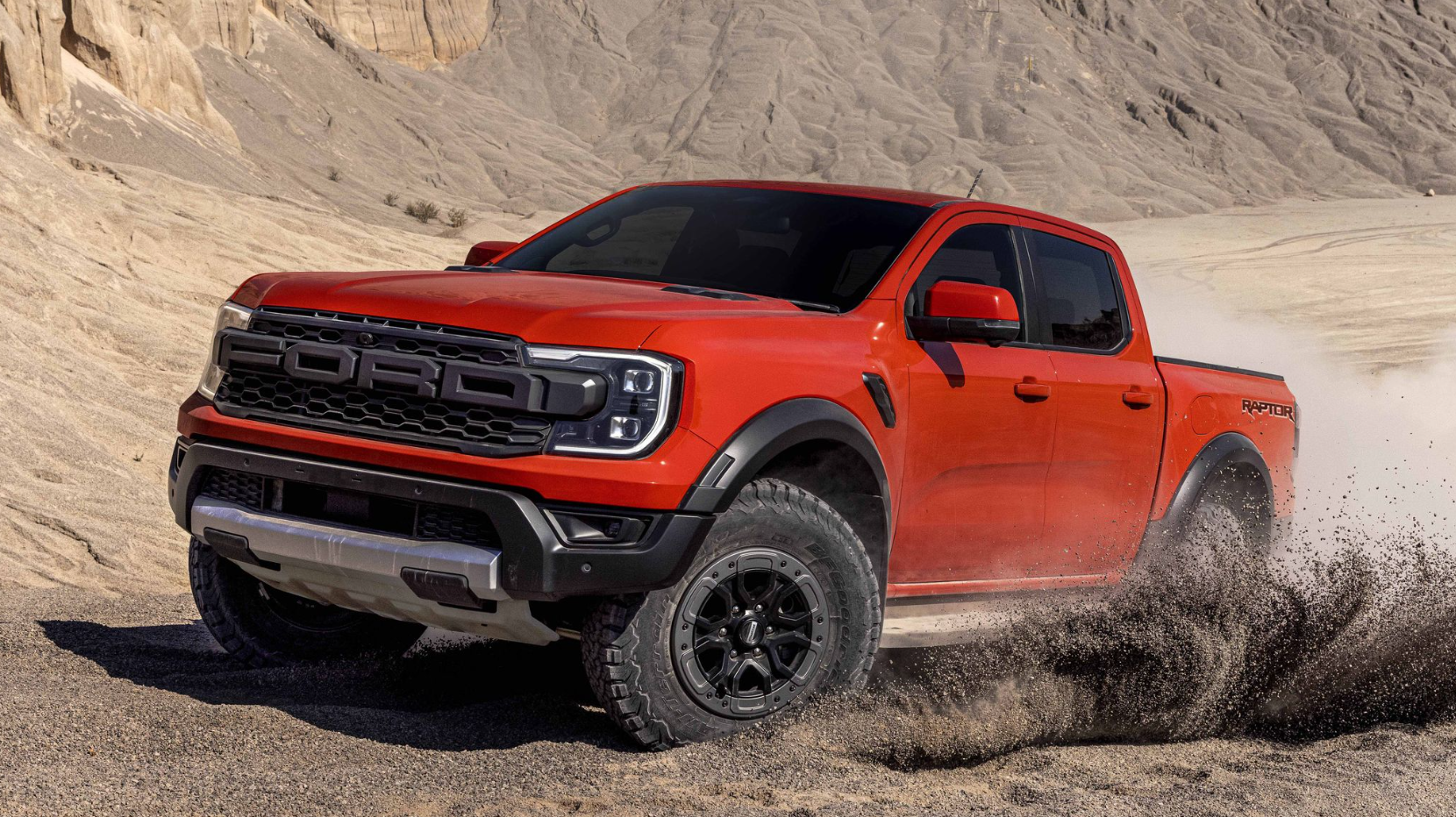 A red 2023 Ford Ranger Raptor spins through a dusty field