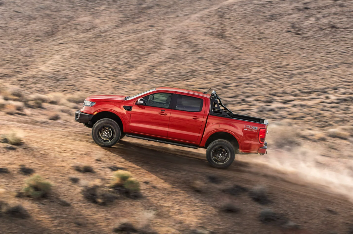 A profile view of a red 2023 Ford Ranger as it tackles a steep incline over rocky terrain